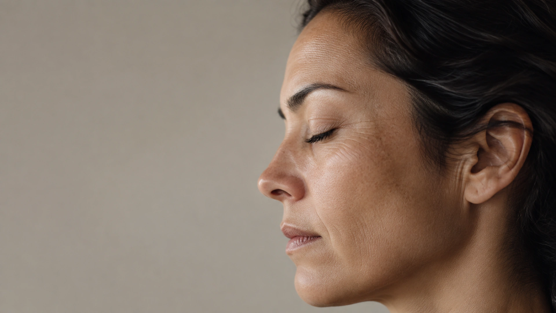 Primer plano de una mujer con los ojos cerrados y una expresión serena y reflexiva.
